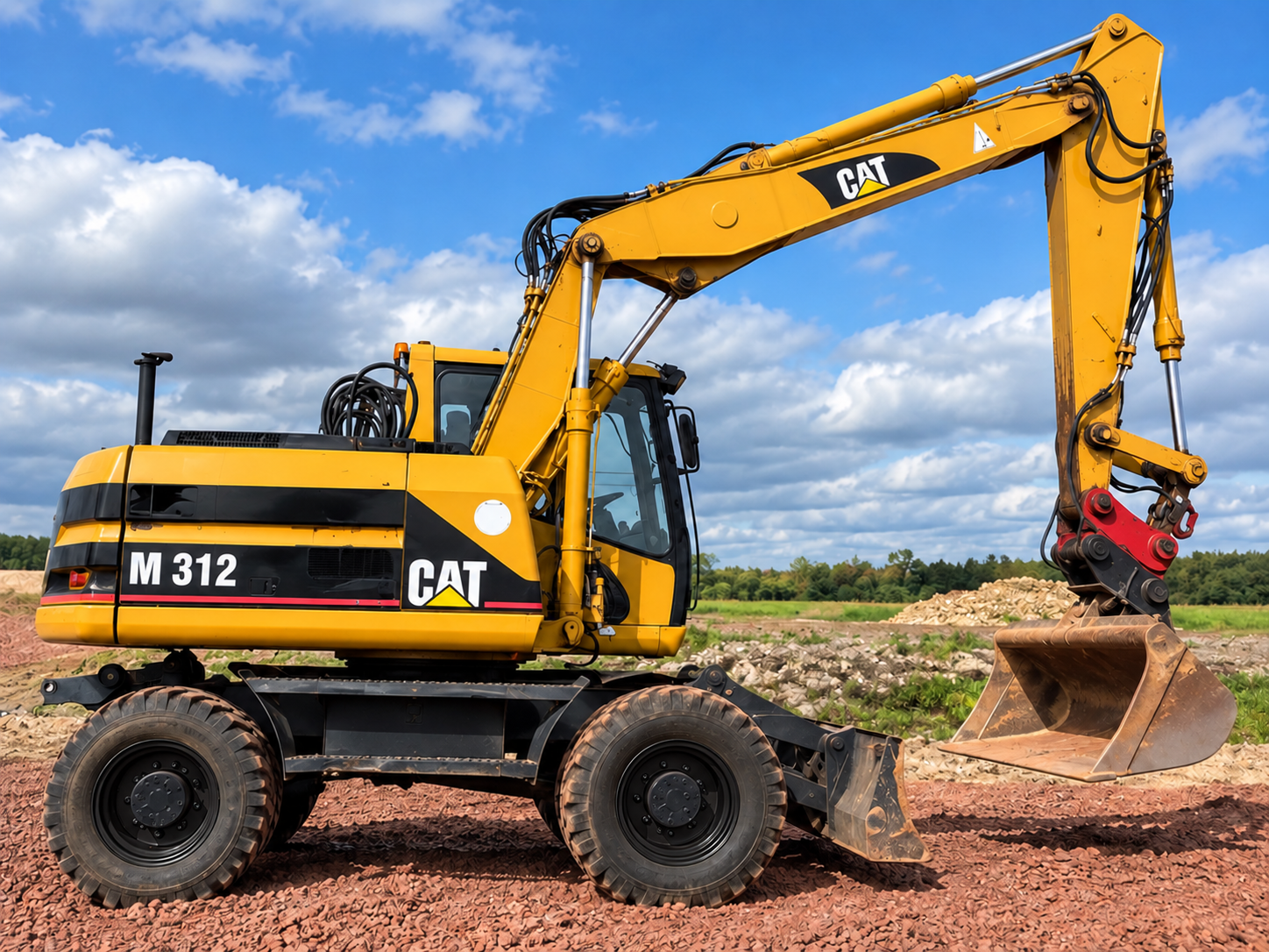 Żółta koparka kołowa CAT M312 na placu robót, widok z boku